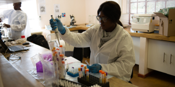 An African woman in a white coat measures kidney function in a lab 600x300
